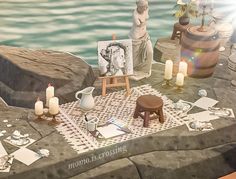 a table with candles, pictures and other items on it next to the water's edge