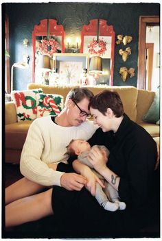 a man and woman sitting on a couch holding a baby