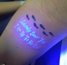 a person's arm with writing on it and blue light coming from behind the arm