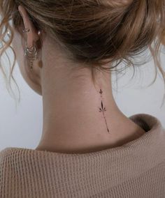 a woman's neck with a small flower tattoo on the back of her neck