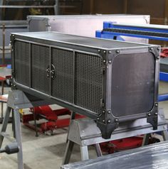 an old tv sitting on top of a metal stand in a factory room with other equipment