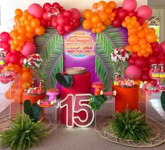 an arrangement of balloons, flowers and decorations for a tropical themed birthday party with the number fifteen