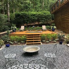 an outdoor patio area with chairs, tables and a fire pit in the middle of it