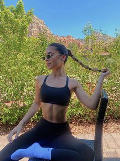 a woman sitting on top of a chair with her hair in the air and wearing sunglasses