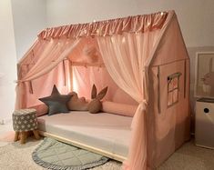 a child's bed with pink canopy and curtains