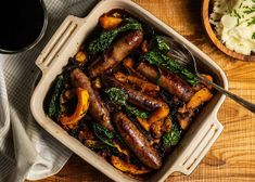 sausages and greens in a casserole dish with a side of mashed potatoes