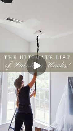 a woman is painting the ceiling in her living room with white paint and black accessories