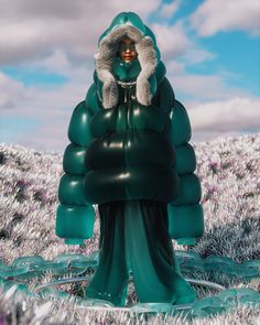 a woman is standing in the middle of a field wearing a green dress and fur collar