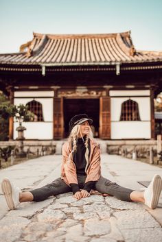 a woman sitting on the ground in front of a building