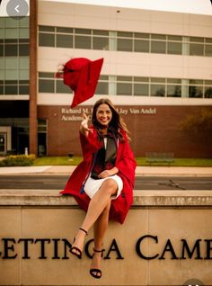 a woman sitting on top of a sign with a red flag in the air above her head