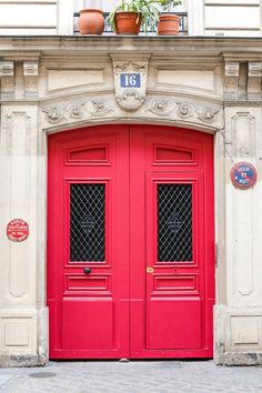 a red door with two potted plants on top