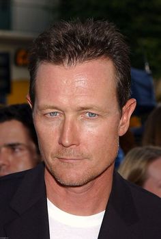 a man in a black suit and white t - shirt looking off to the side