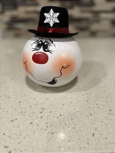 a painted snowman with a top hat on it's head sitting on a counter