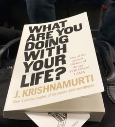 a book sitting on top of a pile of luggage next to a bag with the title what are you doing with your life?