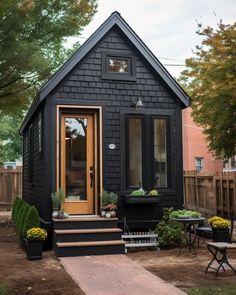 a small black house sitting in the middle of a yard