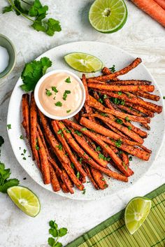 carrots with dipping sauce on a plate next to sliced limes and cilantro