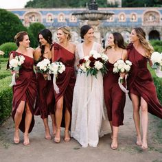 a group of women standing next to each other in front of a fountain with flowers