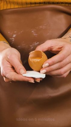 a woman holding an egg shell in her right hand while sitting on a brown leather chair