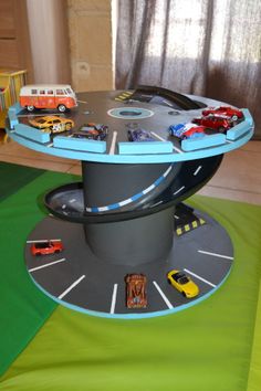 a table with cars and trucks on it in the middle of a play area for children