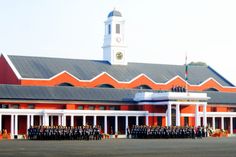 a group of people standing in front of a red and white building with a clock tower