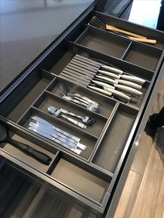 an open drawer with utensils and silverware in it