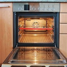 an oven with the door open and it's light on in a wood kitchen