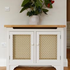 a potted plant sitting on top of a white cabinet next to a wooden floor