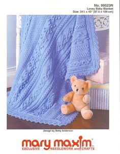 a crocheted teddy bear sitting under a blanket