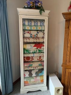 a tall white cabinet with colorful fabric on it