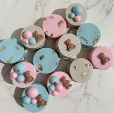 some cupcakes are decorated with teddy bears and blue, pink, and white icing