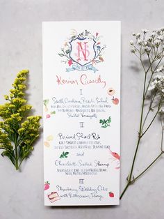 a wedding program with flowers and greenery on the side, next to it is a letter n