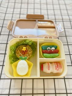 a bento box filled with food on top of a tiled floor next to a table