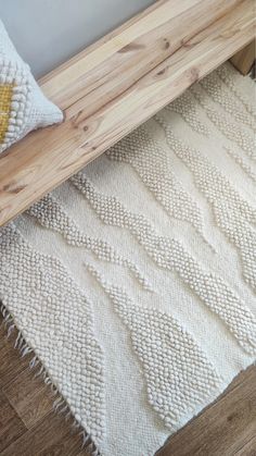 a wooden bench sitting next to a white rug on top of a hard wood floor