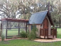 a small house with a chicken coop in the yard next to some trees and grass