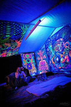 two people are sitting under a tent with colorful lights on the walls and ceiling, while another person sits in front of them