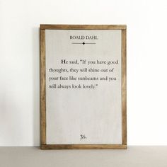 a wooden frame with a poem written in black ink on it, against a white wall