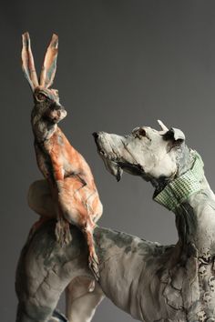 two sculptures of dogs with their heads touching each other