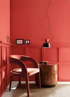 an orange chair and table in front of a red wall