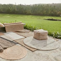 several woven hats and rugs sit on the ground in front of a grassy field