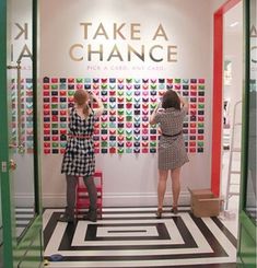 two women are standing in front of a wall that has different designs on it and the words take a chance