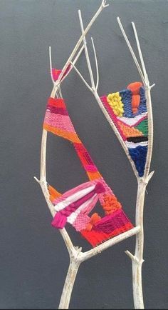 a piece of art made out of yarn hanging from a tree branch