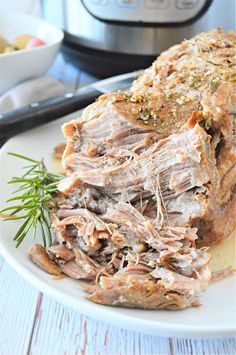 slow cooker pork roast on a white plate with rosemary sprigs next to it