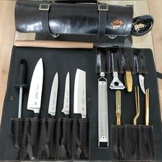 an assortment of knives in a leather case on a table next to a knife sharpener