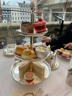 three tiered trays filled with cakes and pastries on top of a table