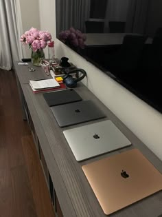 several apple laptops are sitting on a long table in front of a large window