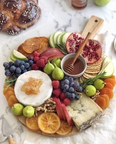 a platter filled with fruit, cheese and crackers on top of a marble table