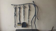 an assortment of metal tools hanging on a wall next to a table with a paintbrush and brush