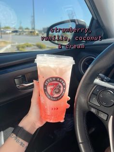 a person holding a drink in their hand while sitting in the driver's seat