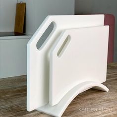 a white plastic cutting board on top of a wooden table next to a knife holder