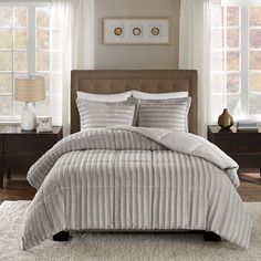 a bed with white and grey comforters in a bedroom